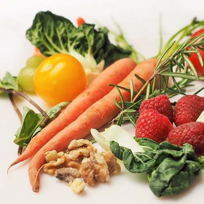 Carots, walnuts, raspberries and tomatoes on a white table