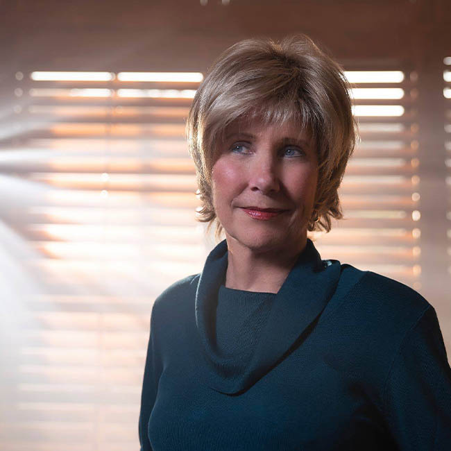 A portrait of Joni Eareckson Tada in front of a window bursting with light