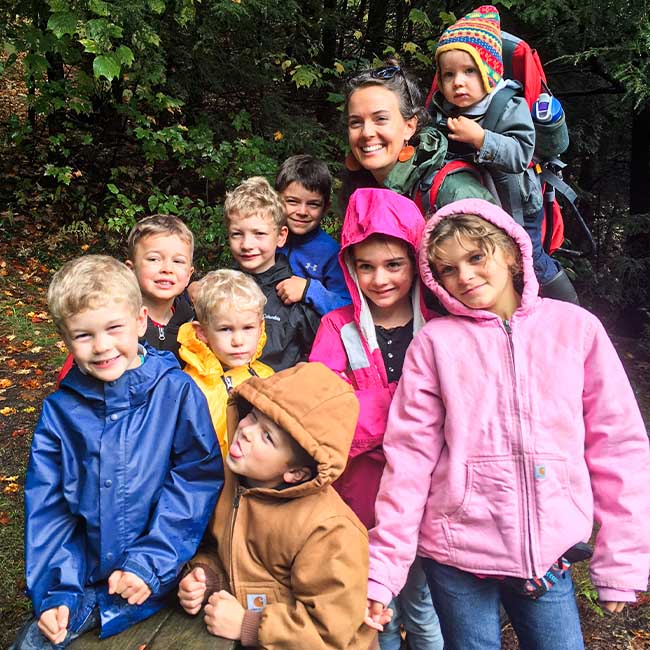 Nine children posing and smiling on a trail with a woman instructor