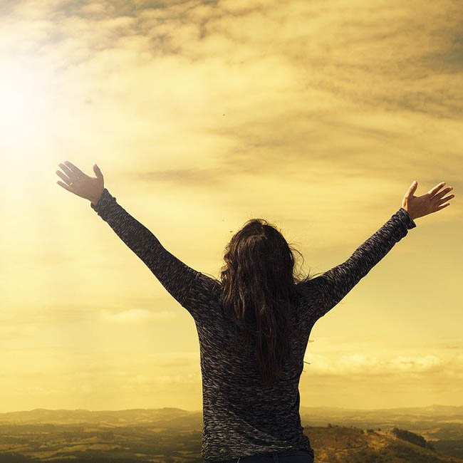 Woman facing away from the camera with her arms outstretched in praise