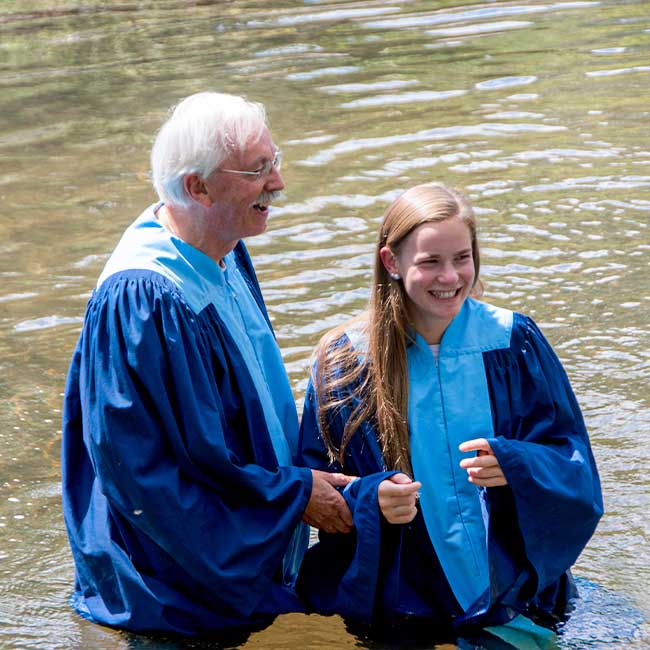 Former Pastor Anderson senior standing in the river with a member of the youth group during a baptism