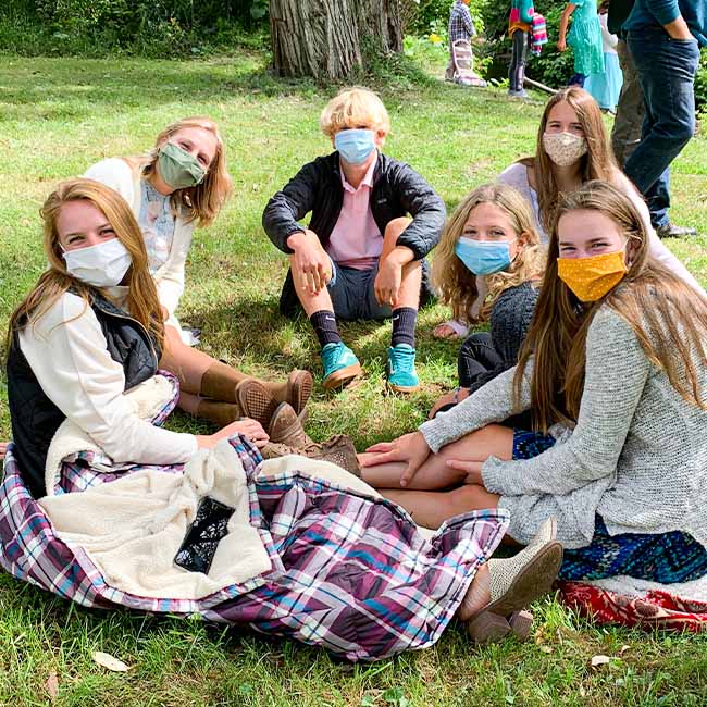 Youth group sitting together outside with masks on during the pandemic